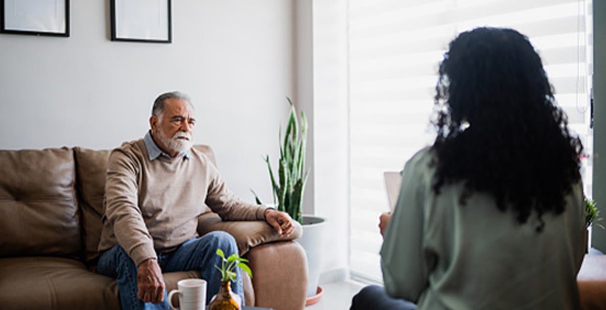 A man sitting on a couch engaged in conversation with a woman.