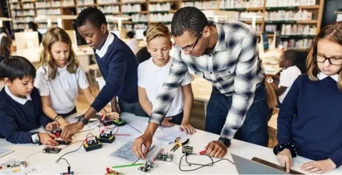 Teacher guiding students in library robotics activity